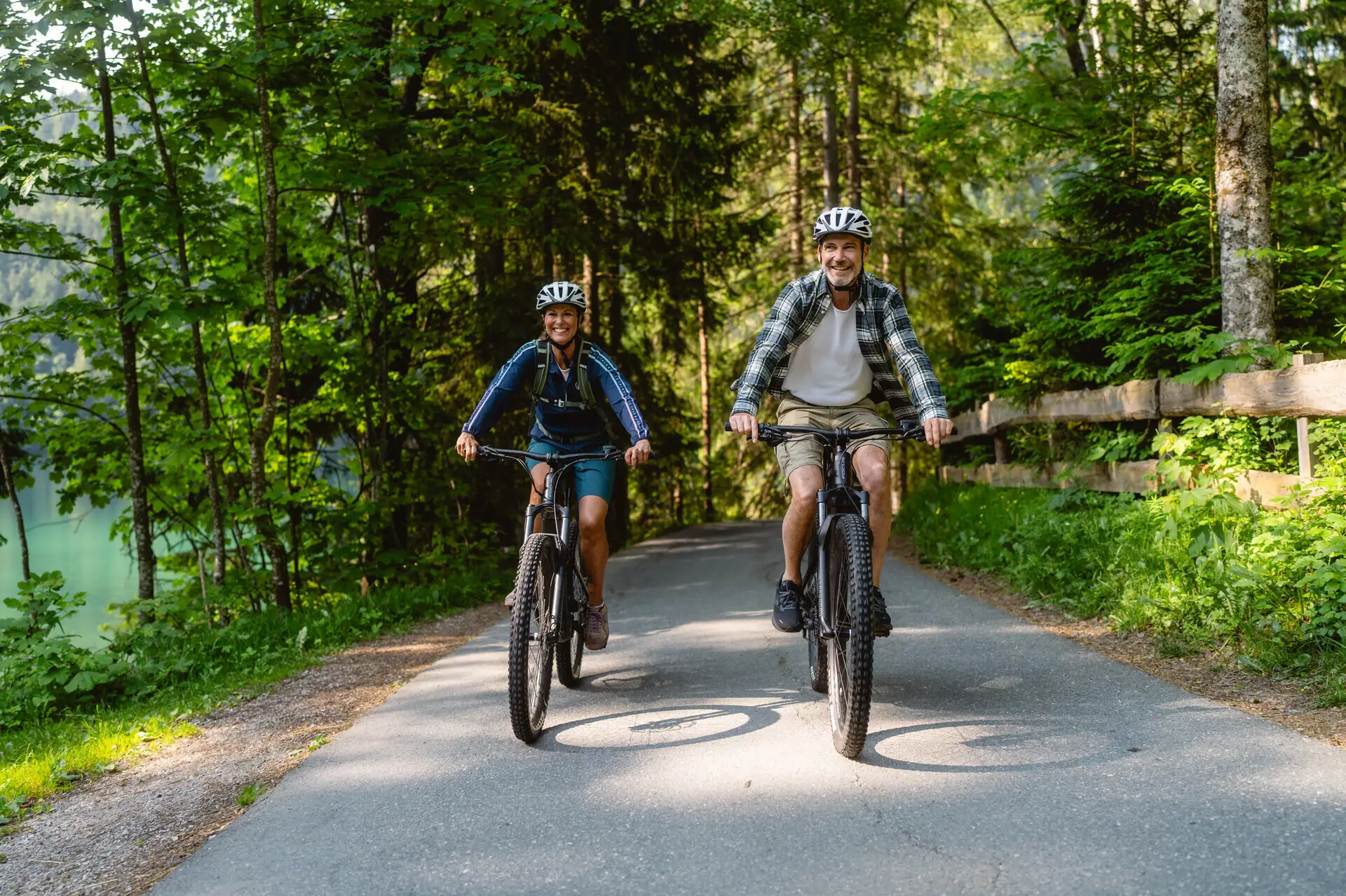 Fietstocht Een man en een vrouw fietsen over een pad met bomen.