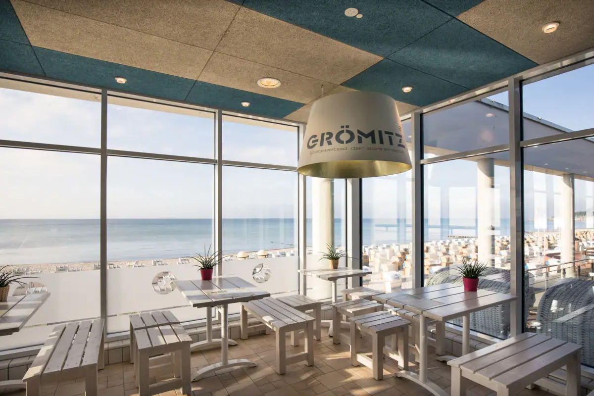 Een kamer met tafels, stoelen en een groot raam.