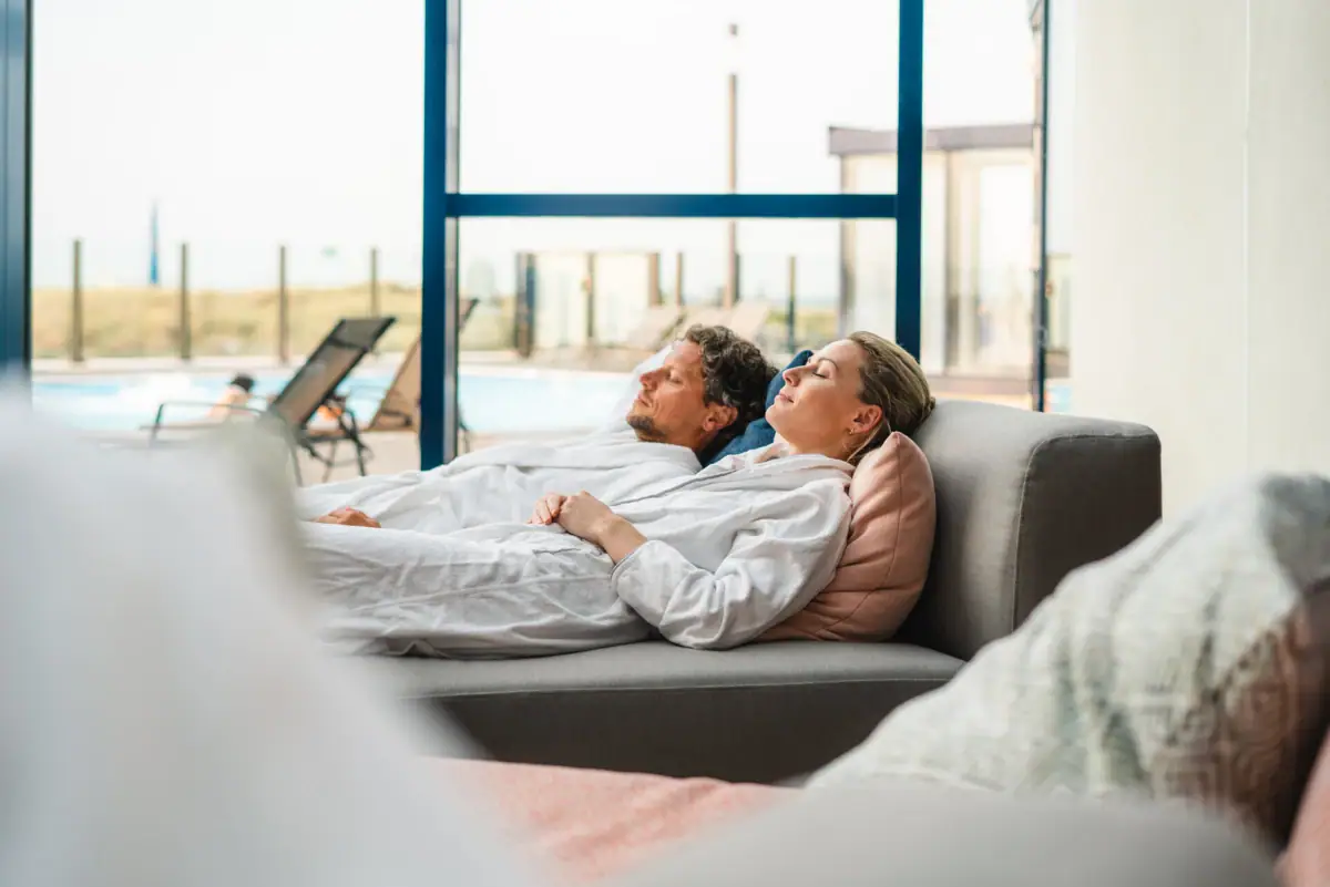Een man en een vrouw liggen op een bank.