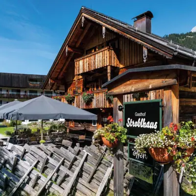 Een rustieke houten hut met een bord en parasols.