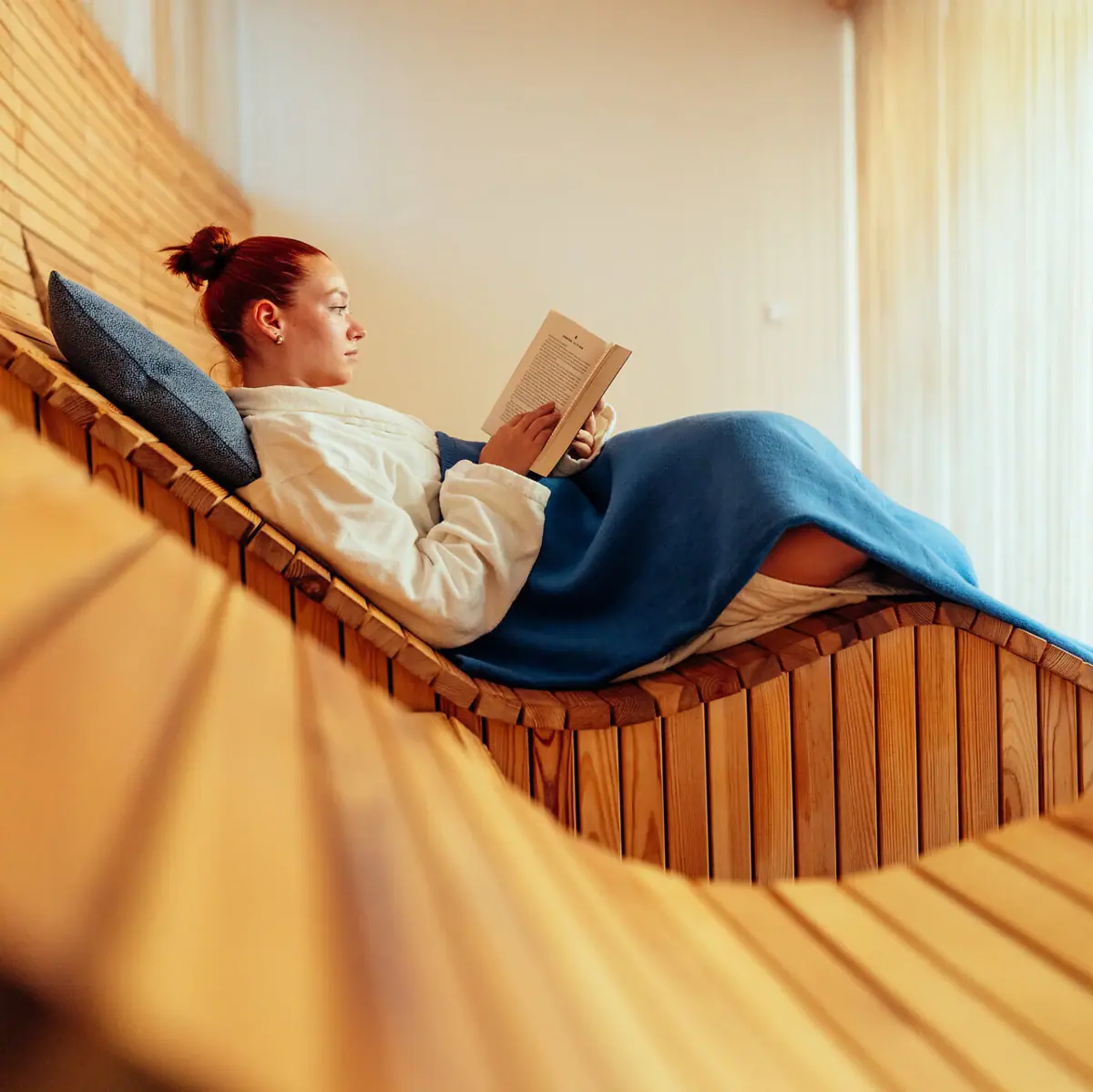 SPA-ligstoel Een vrouw zit op een houten bankje een boek te lezen.