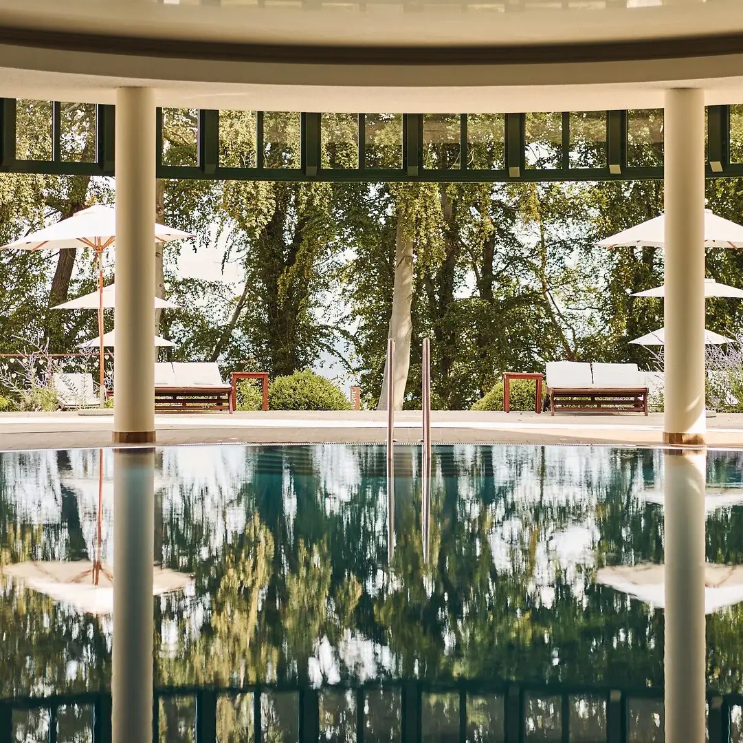 Binnenzwembad aja Nordperd & Villa's Een zwembad met parasols en stoelen op de achtergrond.