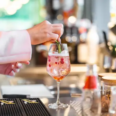 Eén persoon legt een blad op een drankje in een wijnglas.