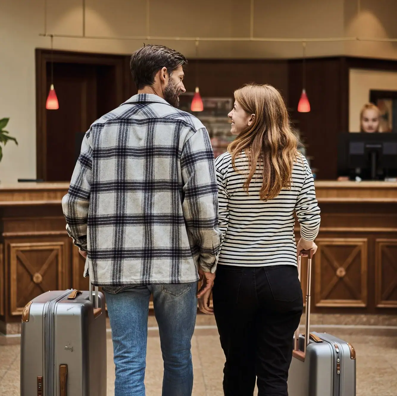 Een man en een vrouw met bagage in een hotellobby.