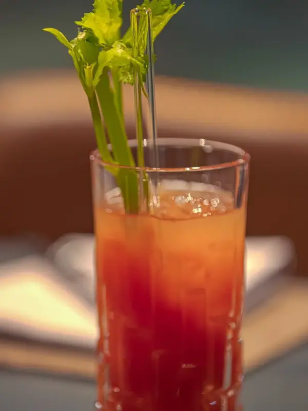 Een glas met een drankje en een groene plant erin.