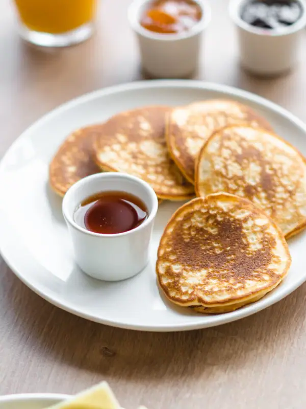 Een bord met pannenkoeken en sauzen op een tafel.