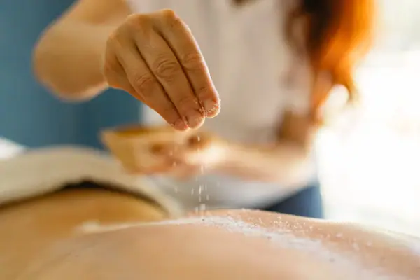 De ene persoon strooit zout op de rug van de andere persoon.