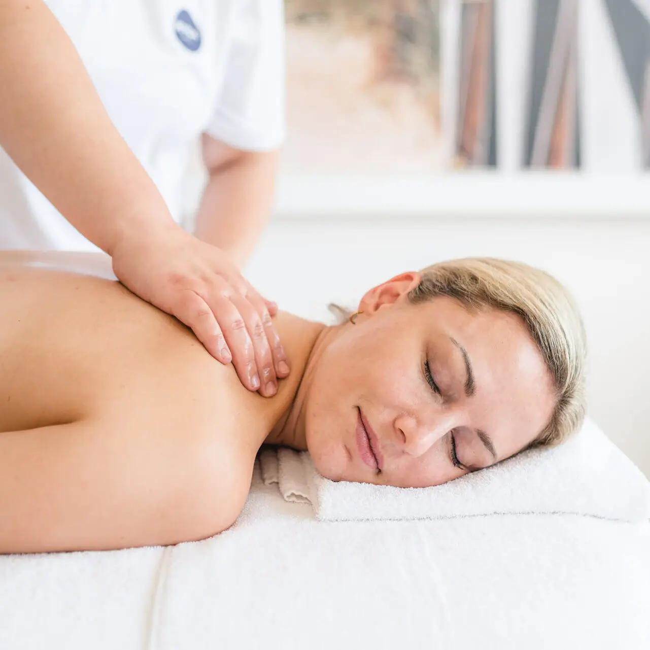 Een vrouw ligt op een witte handdoek met haar ogen dicht.