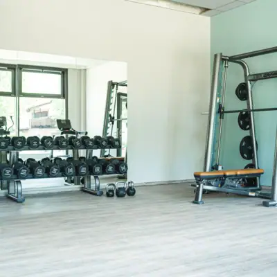 Sterktebereik Een fitnessruimte met gewichten en een plank vol apparatuur.