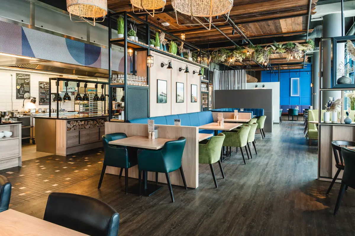 Restaurant bij aja Warnemünde Een restaurant met tafels en stoelen. Het open buffet met lampen is te zien op de achtergrond.