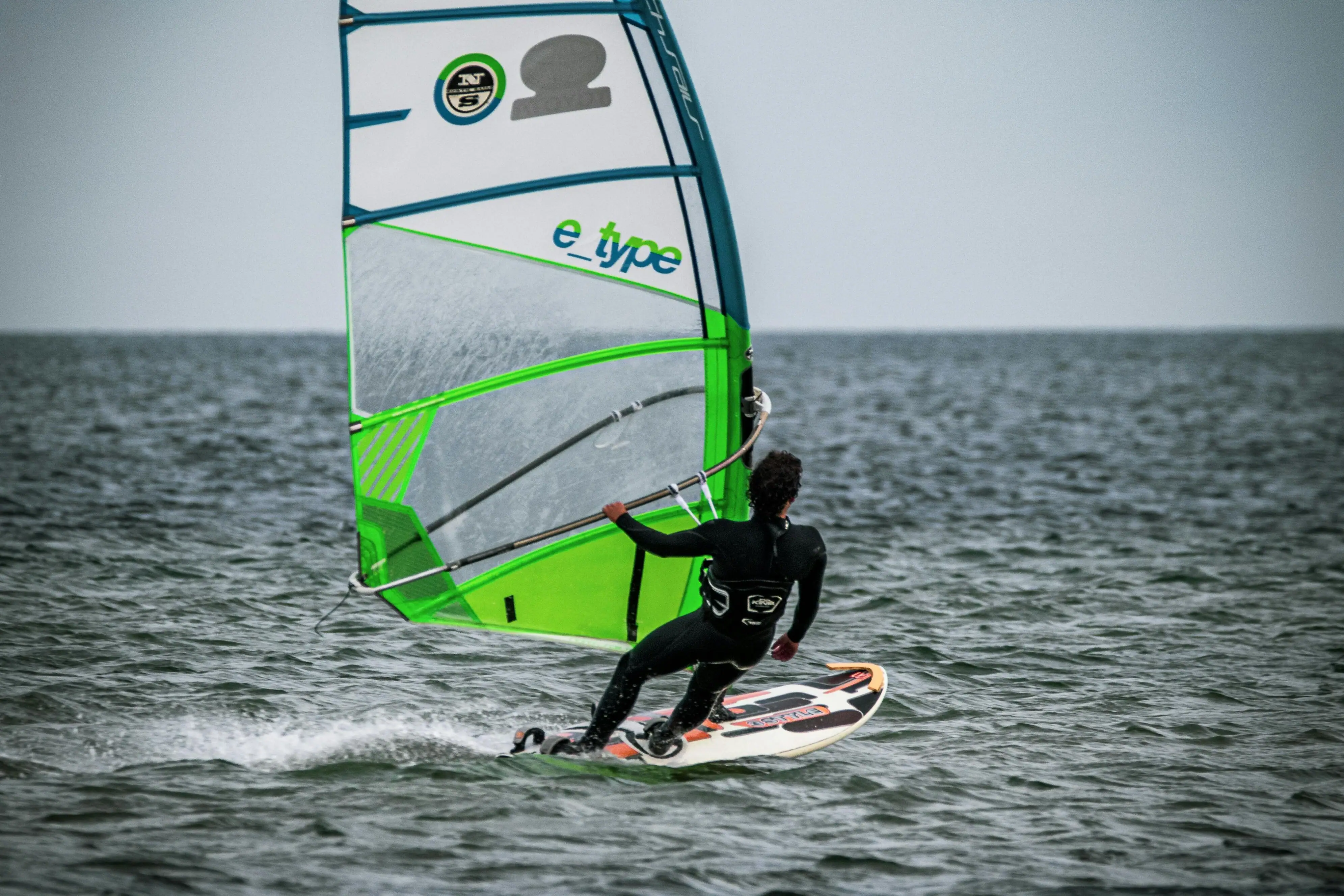 Een persoon op een surfplank met een zeil.