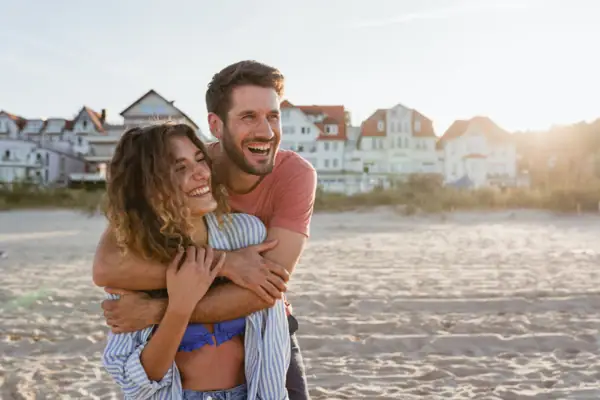 Een man en een vrouw omhelzen elkaar op het strand.