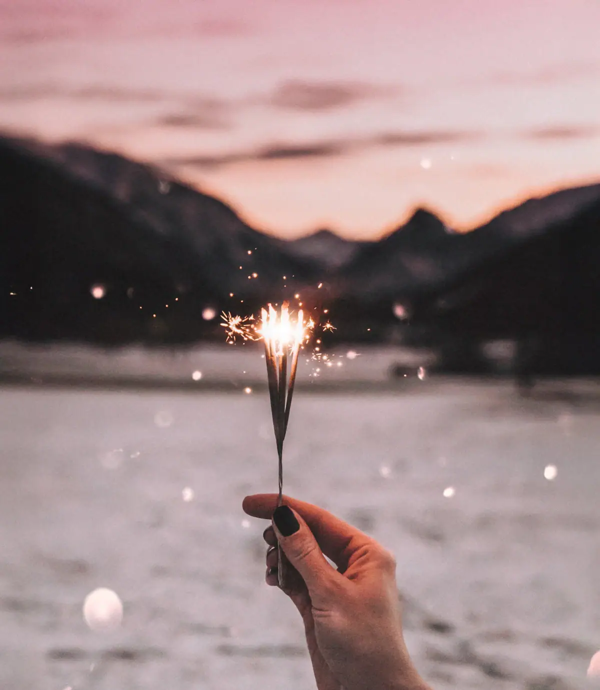 Hand die een fonkelaar vasthoudt tegen een hemel met de bergen op de achtergrond