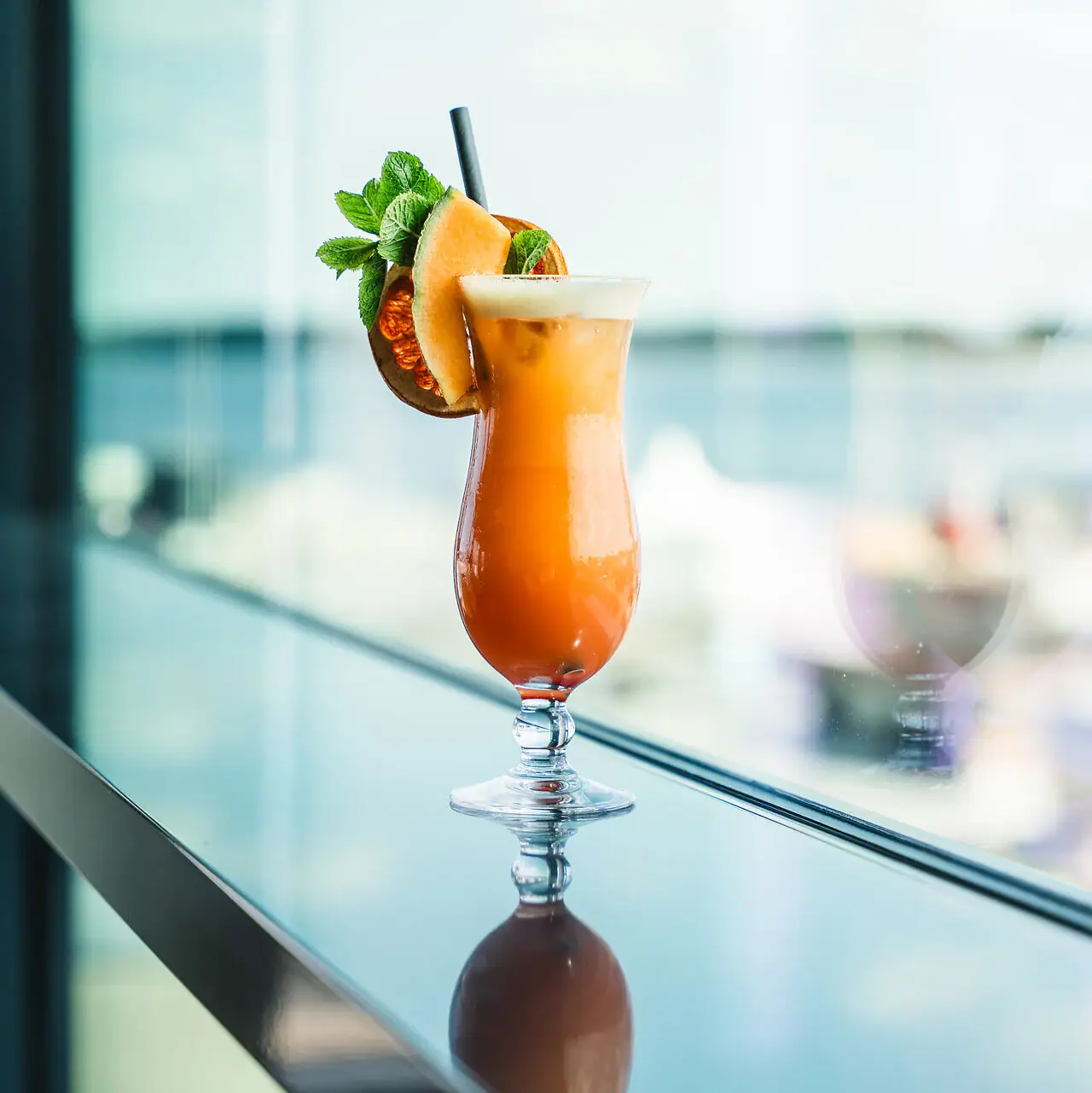 Een glas met een cocktail en garnering op tafel.