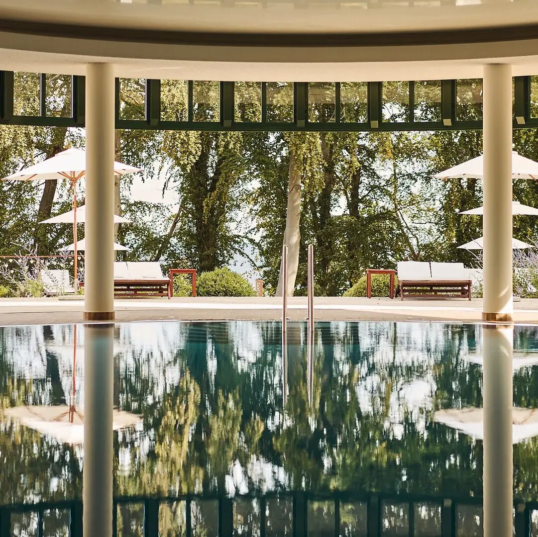 Een zwembad met parasols en stoelen op de achtergrond.