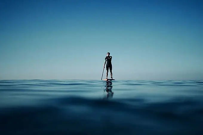 Een persoon op een paddleboard in de oceaan.