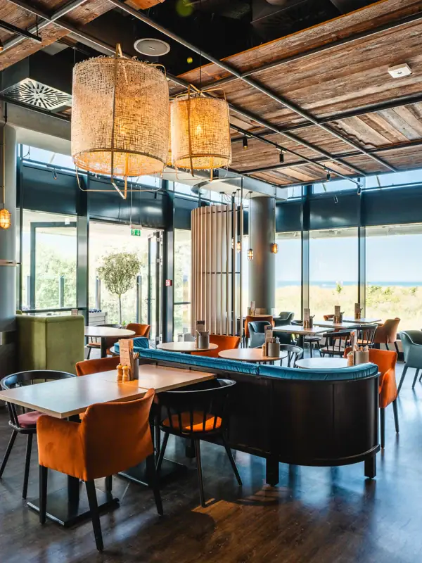 Restaurant en bar bij aja Warnemünde Een restaurant met tafels en stoelen. Modern en maritiem ingericht.