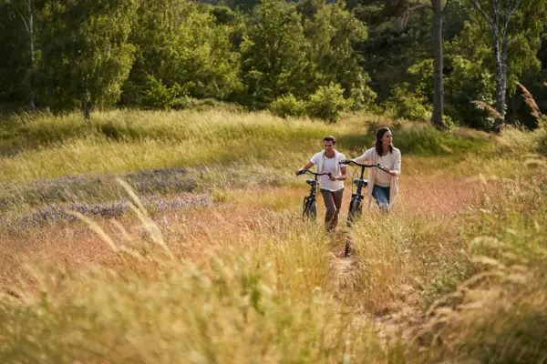 Een man en een vrouw fietsen door hoog gras.
