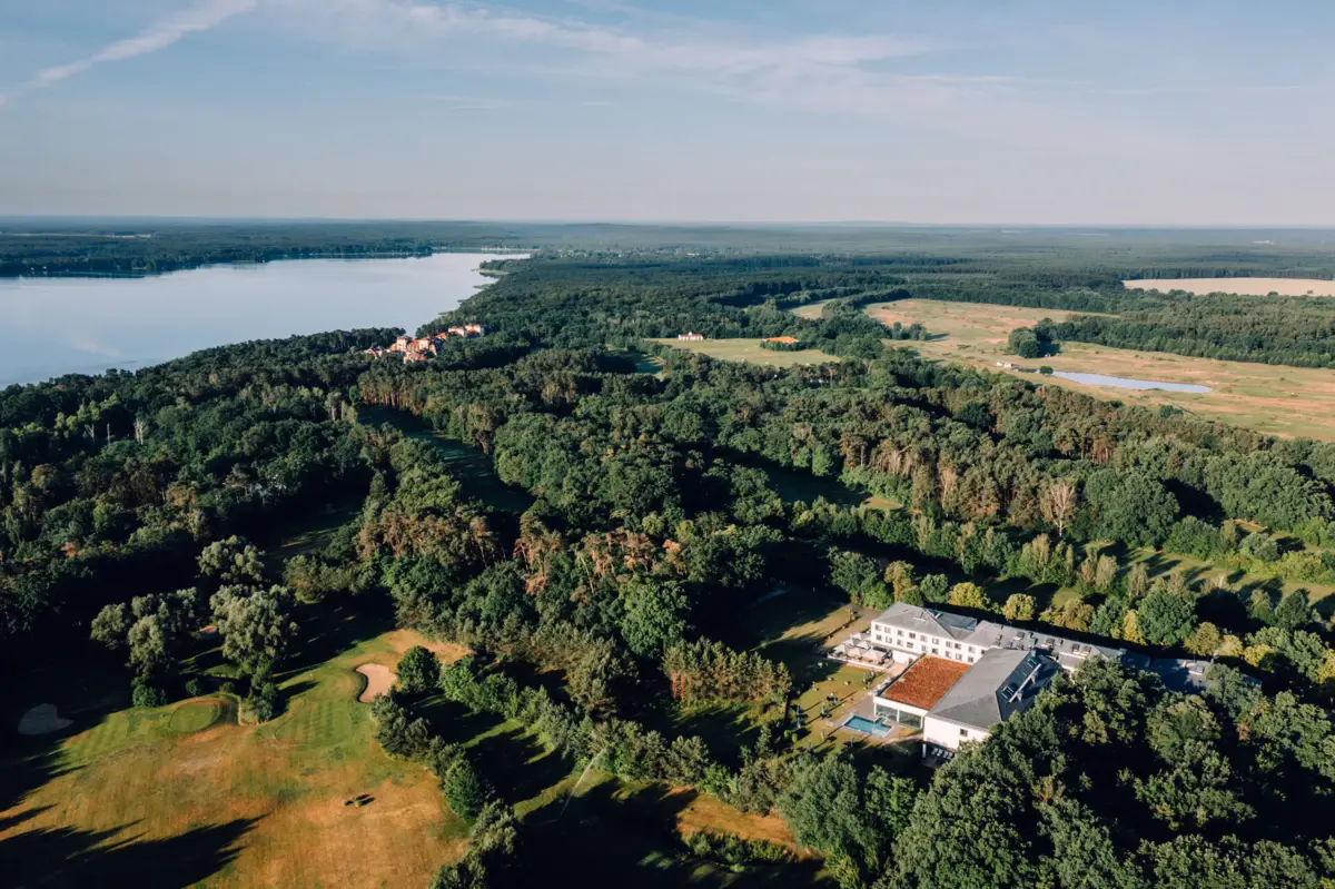 Een groot gebouw omringd door bomen en water.