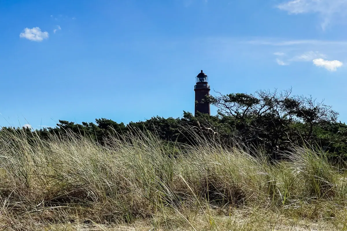 Een vuurtoren op een grasveld onder een bewolkte hemel.