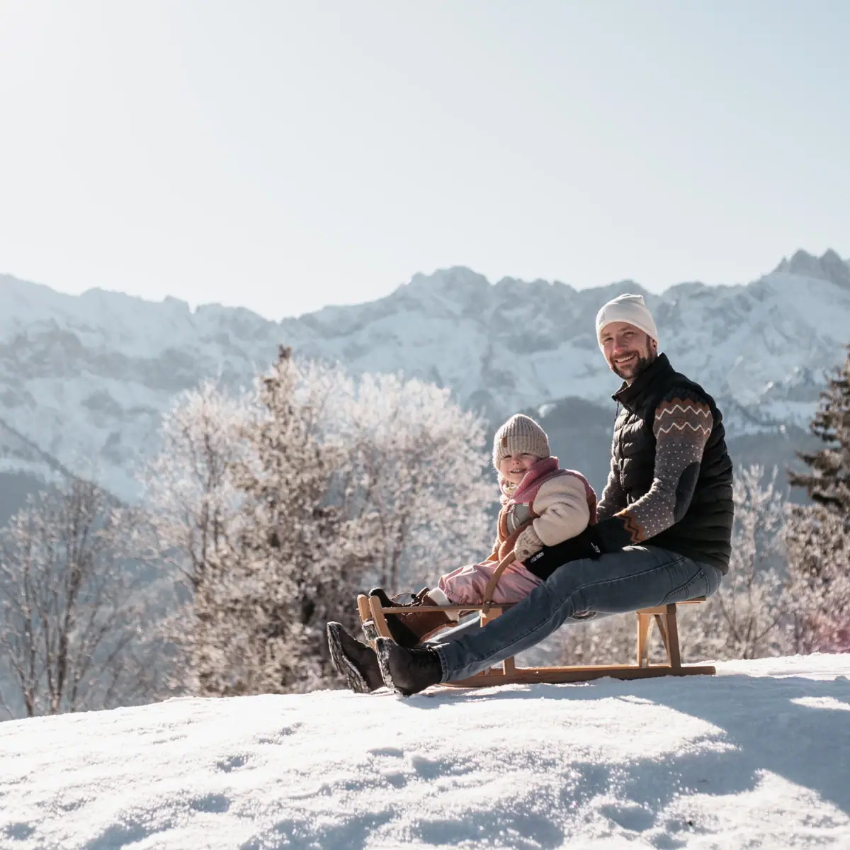 Een vader met zijn dochter op een slee tijdens een gezinsvakantie in Garmisch-Partenkirchen.