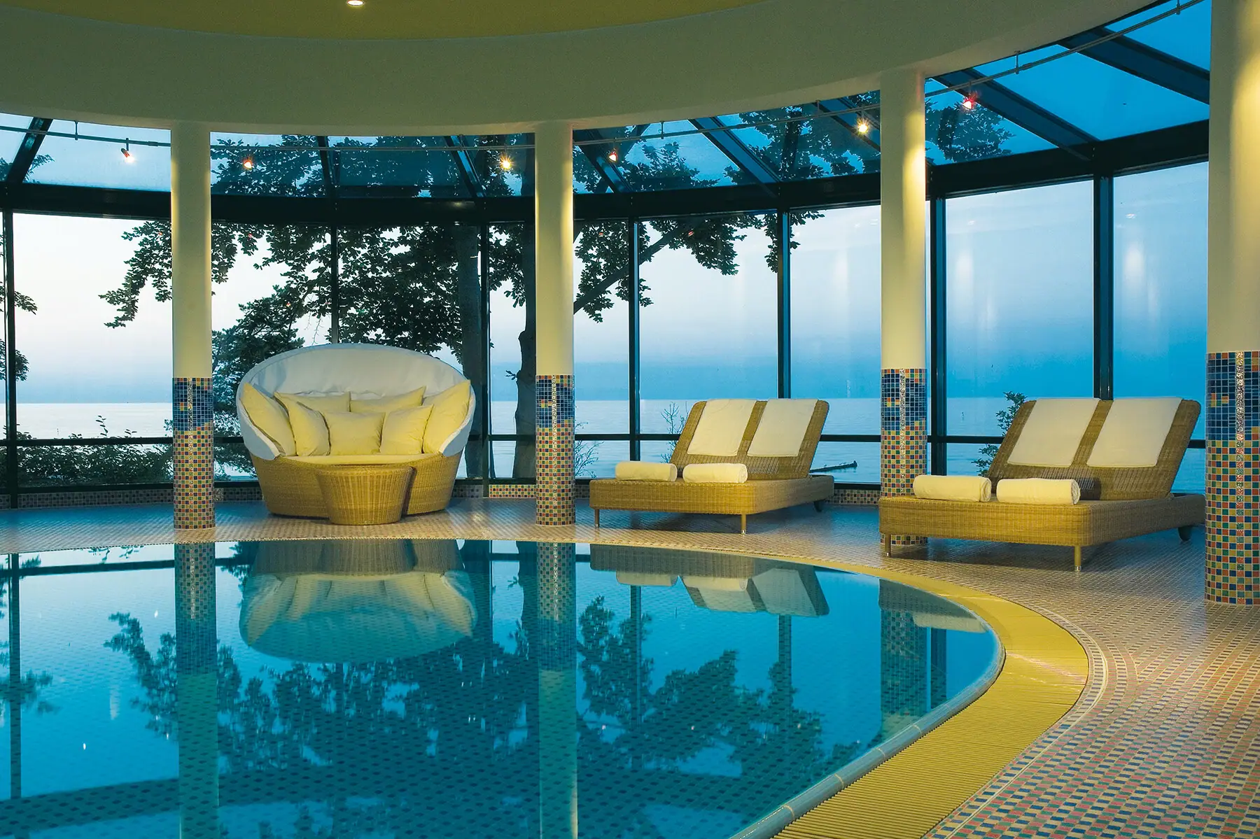 Zwembad met stoelen en een groot raam.