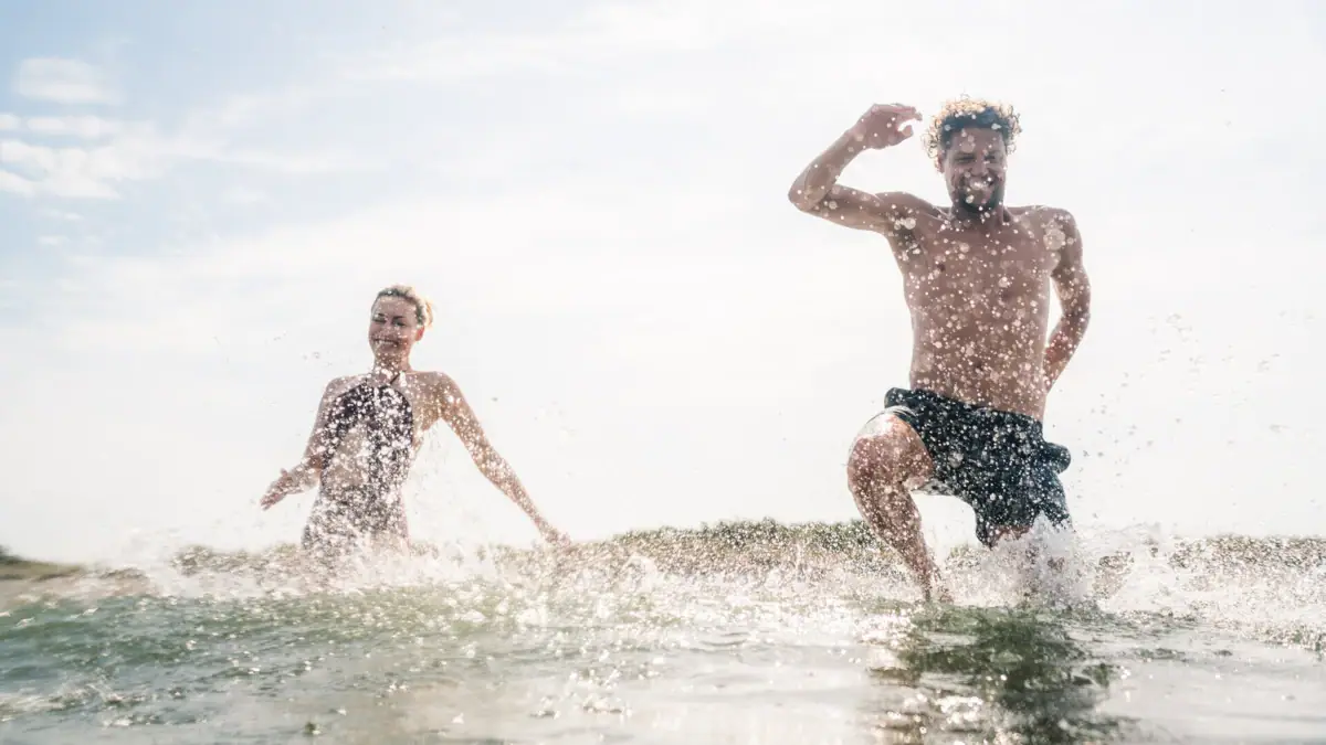 Twee mensen lopen in het water.