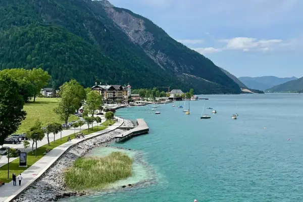 Achensee oever Een waterlichaam met een pad en boten erop.
