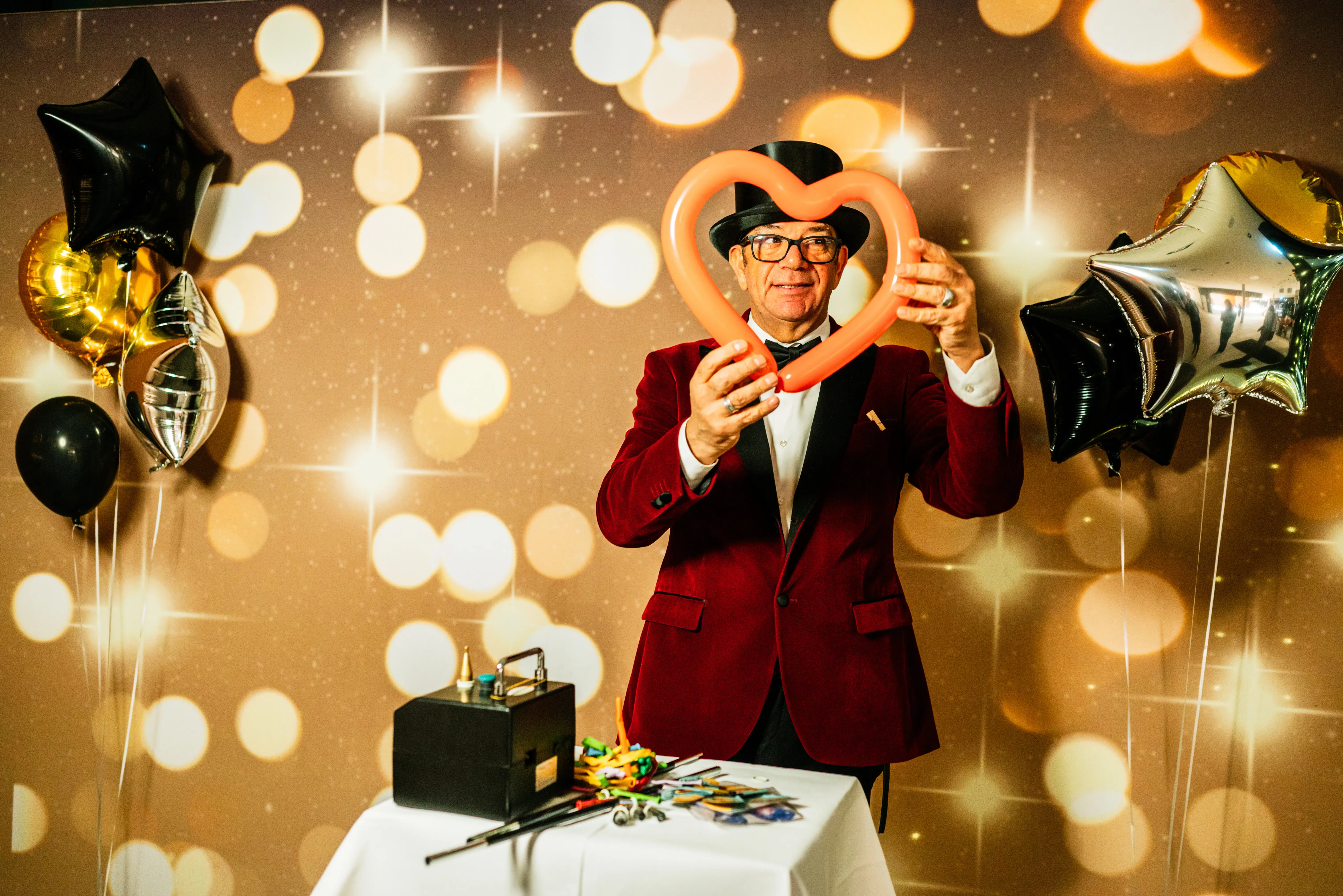 Een man in een rood pak maakt figuren van lange ballonnen