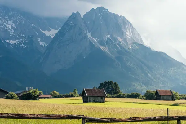 Alpspitzblick & Tegernauweg Een houten hek in een veld met bergen op de achtergrond.