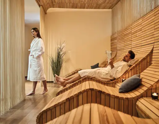 Werfenweng wellness Een man en een vrouw in een kamer met houten banken.