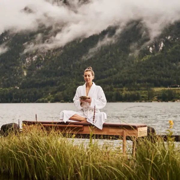 Yoga Een vrouw zit op een bankje bij het meer.