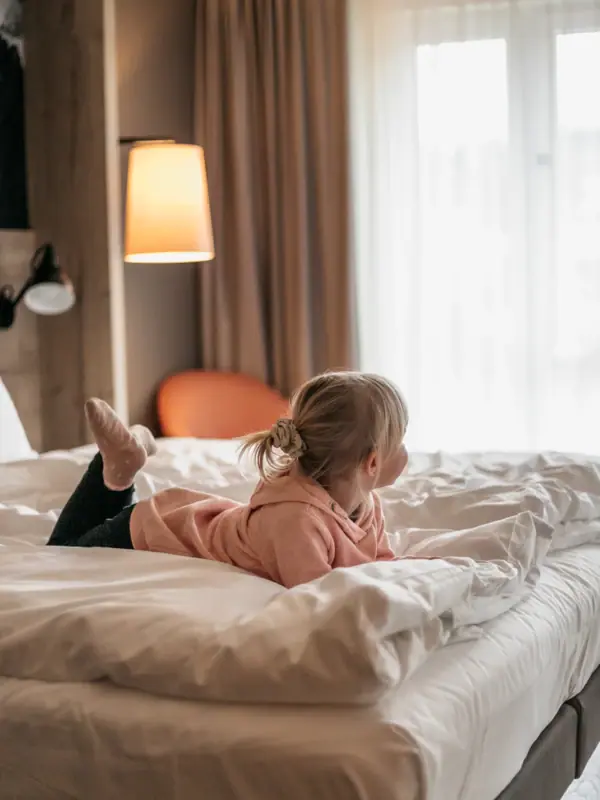 Een kind ligt op een bed in een Aja-familiehotel in Beieren.