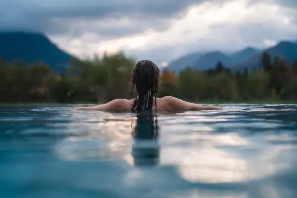 Wellness aja Ruhpolding Een vrouw zwemt in het zwembad van het aja Ruhpolding met uitzicht op de bergen.