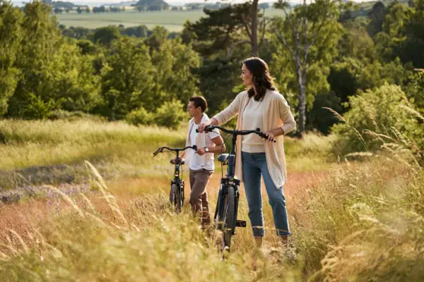 Een stel met fietsen staat midden in een zomers weidelandschap op Rügen; ze genieten in de buitenlucht van het uitzicht over het heuvellandschap en de bloeiende velden.