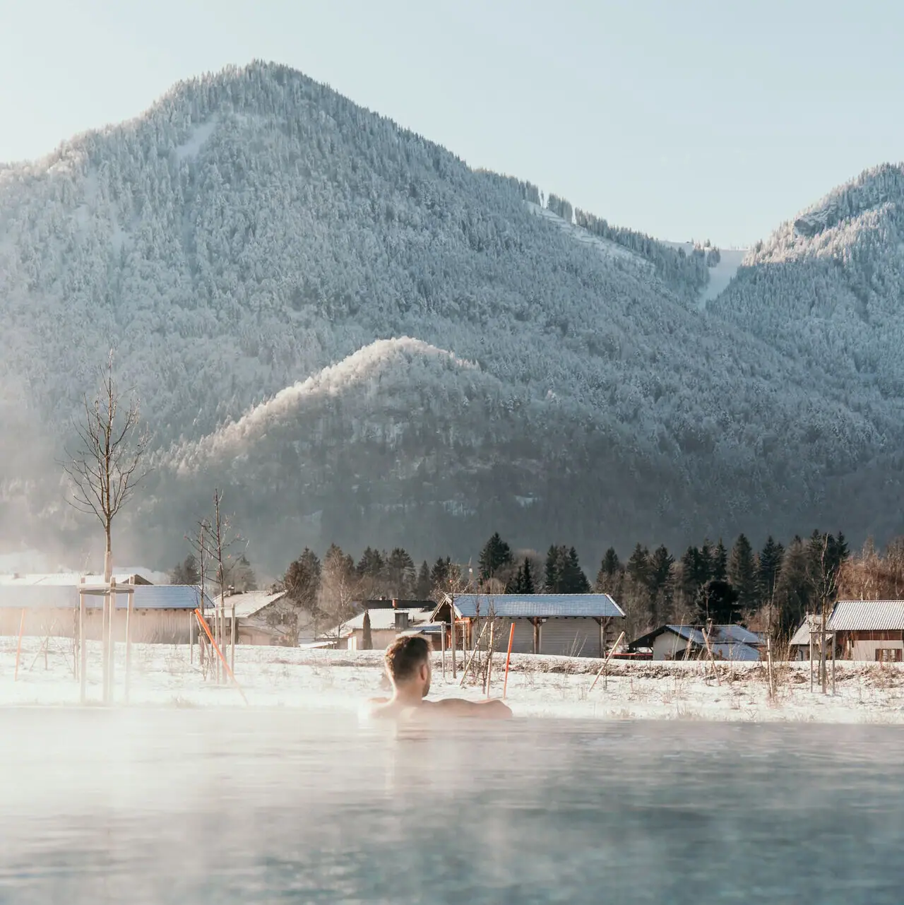 Buitenzwembad in de winter Een persoon in een zwembad met bergen op de achtergrond.