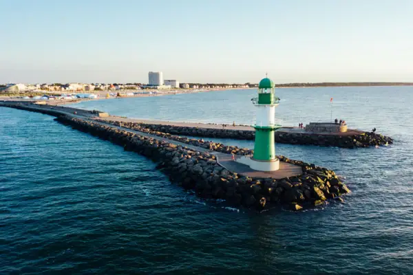 Warnemünde Leuchtturm Grüner und weißer Leuchtturm auf Felsen im Wasser.