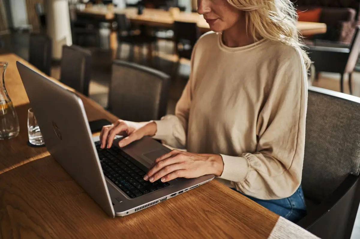 Een vrouw zit aan een tafel en gebruikt een laptop.