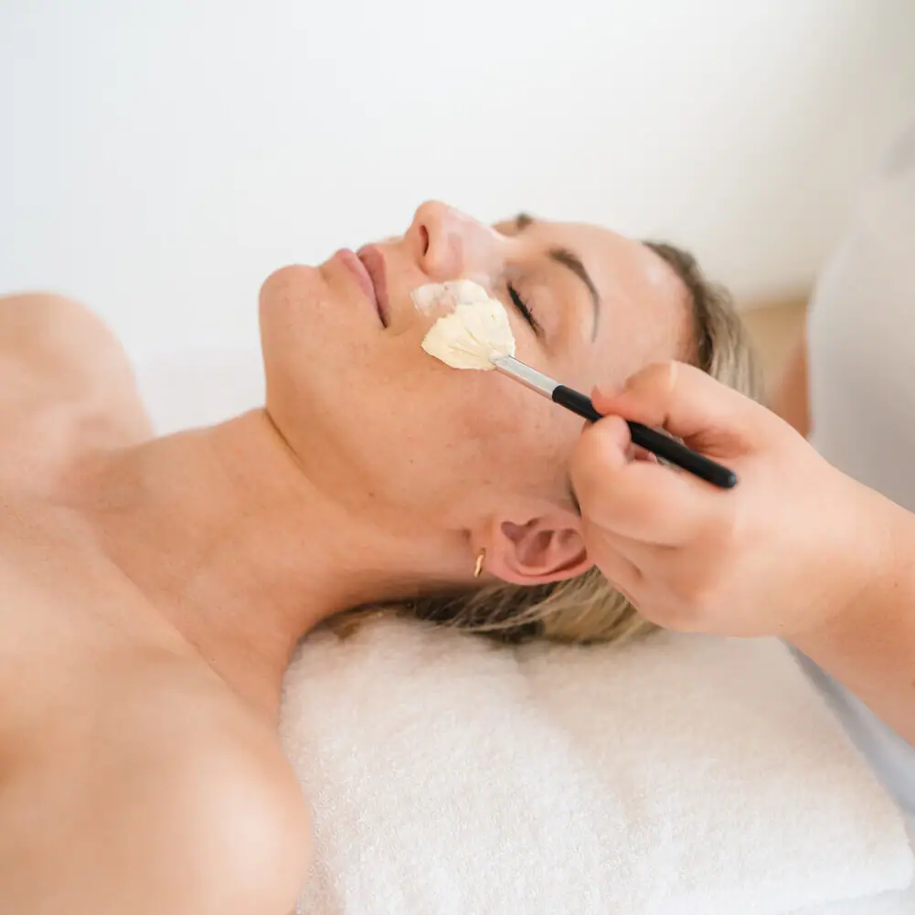 Een vrouw ligt met een verfkwast op haar gezicht.