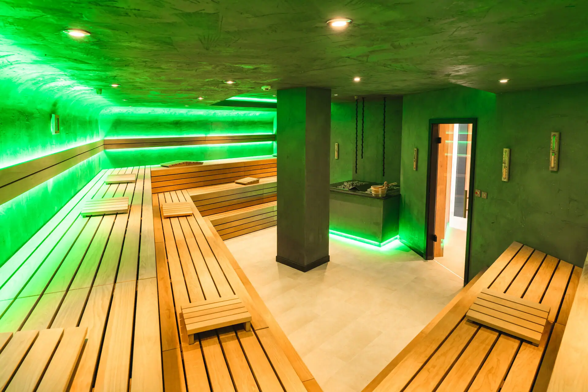 Sauna Een kamer met groene muren en houten banken.