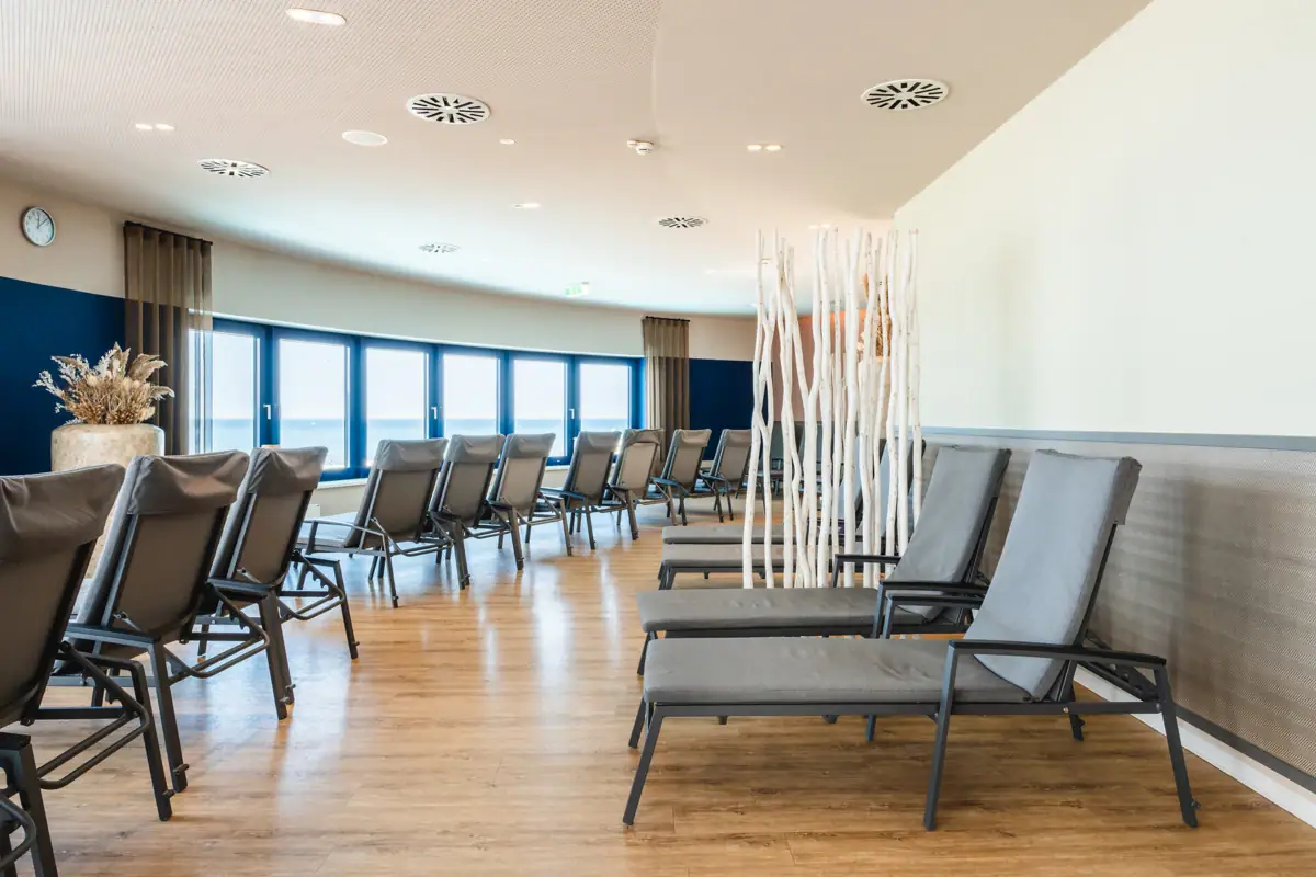 Ontspanningsruimte bij de aja Warnemünde Een kamer met ligstoelen en ramen.
