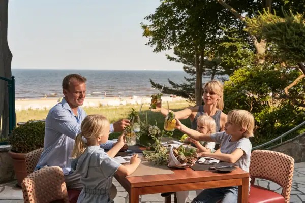 Een gezin zit aan een tafel met drankjes in het aja Strandhotel Bansin.