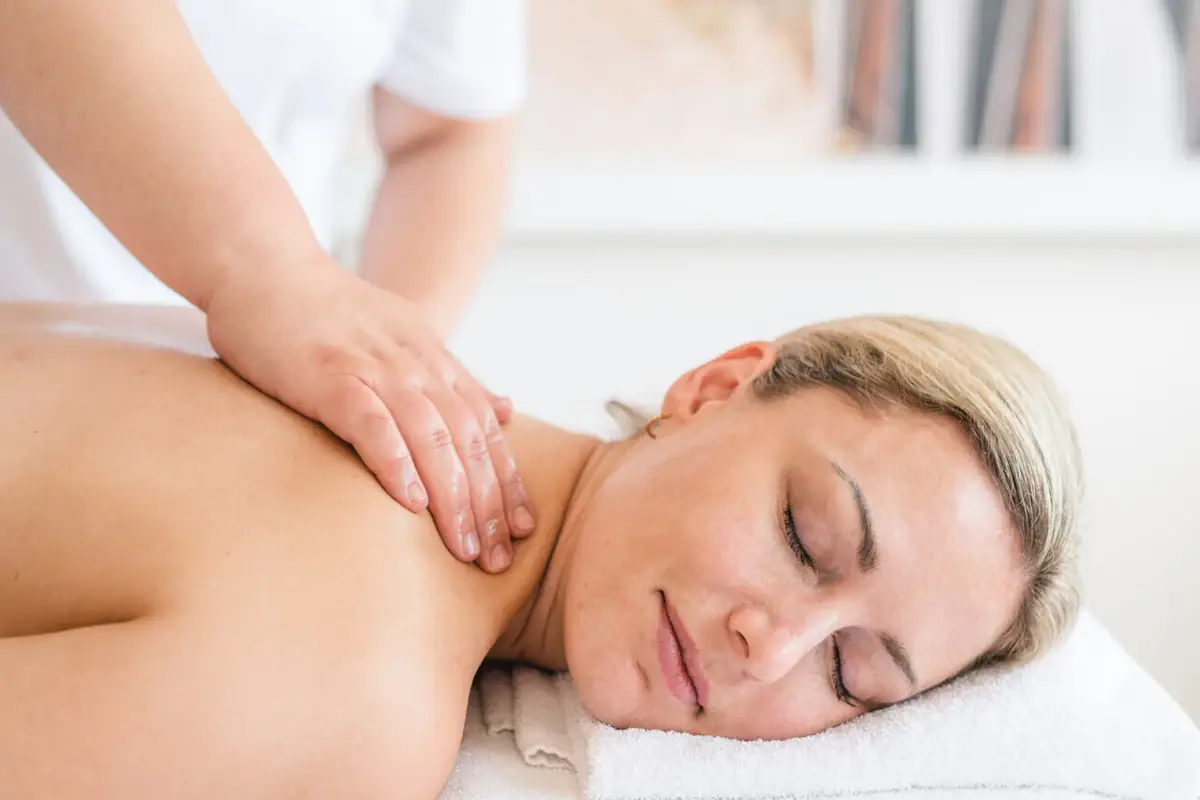aja SPA-toepassing Een vrouw ligt op een witte handdoek met haar ogen dicht.
