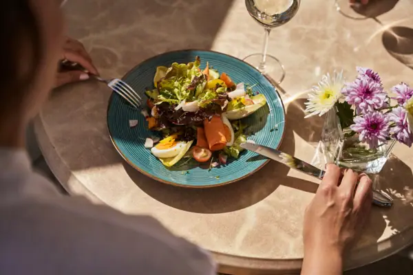 Een bord met salade en een glas wijn.