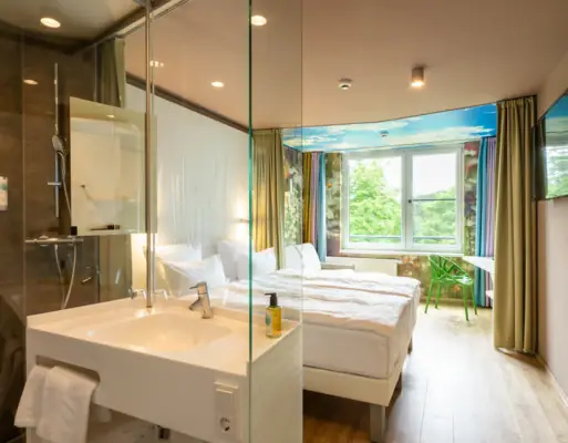 Een kamer met een glazen douche en twee bedden.