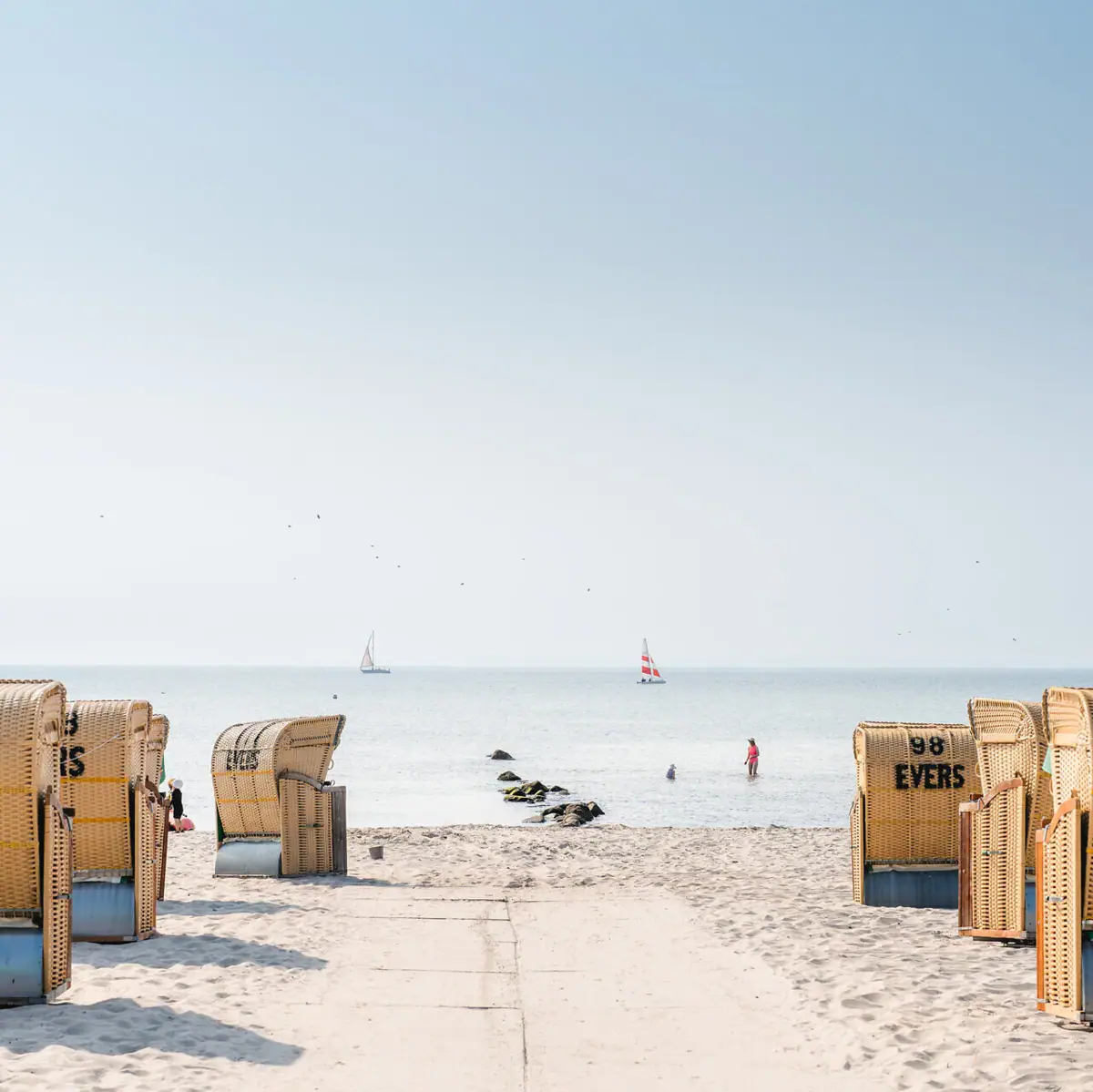 Een strand met veel manden en een watermassa.