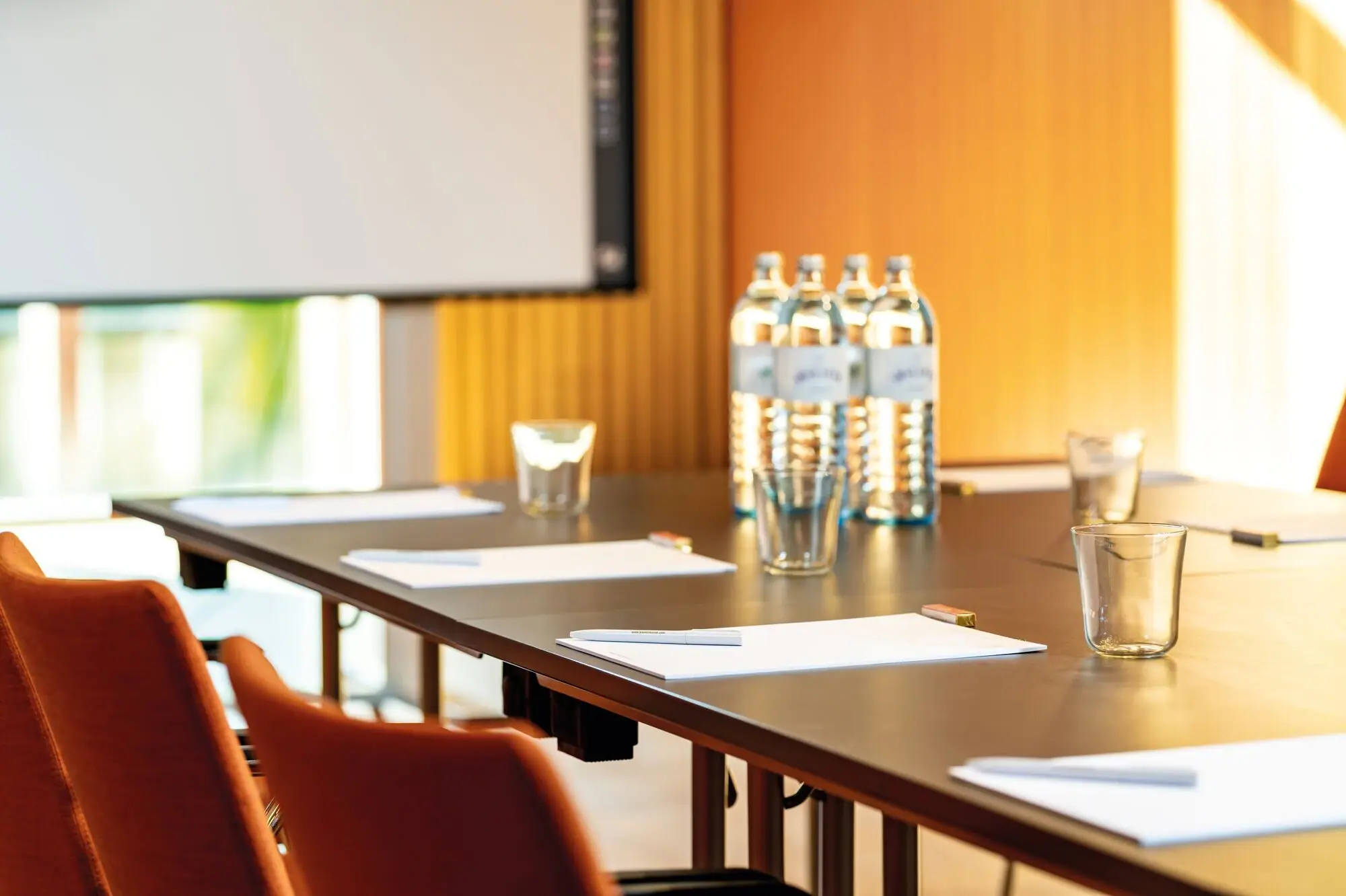 Conferentieruimte Een tafel met papieren en glazen erop.