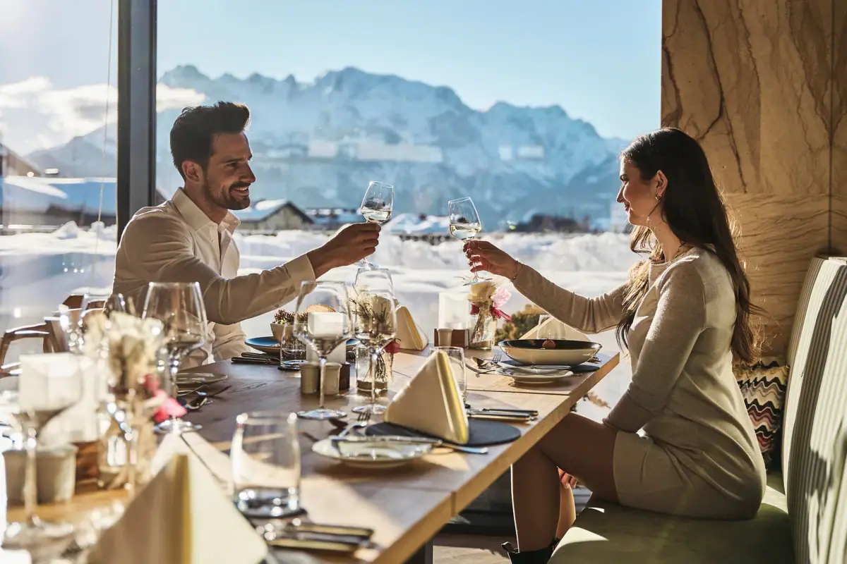 Een man en een vrouw zitten aan een tafel met glazen wijn.