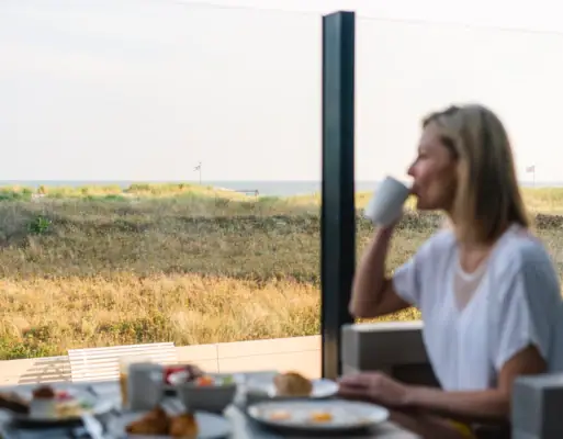 Ontbijt bij aja Warnemünde Een vrouw zit aan een tafel met een kop koffie.