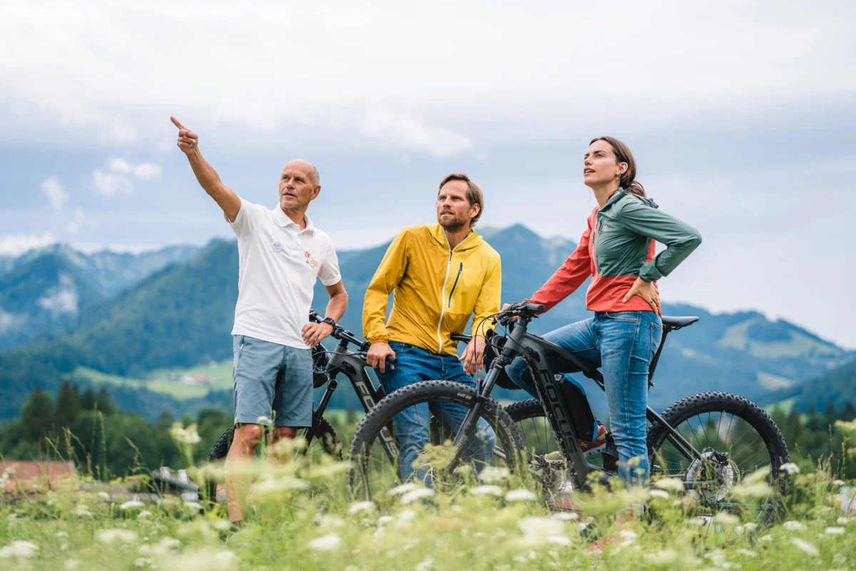 Een groep mensen staat in een veld met fietsen.